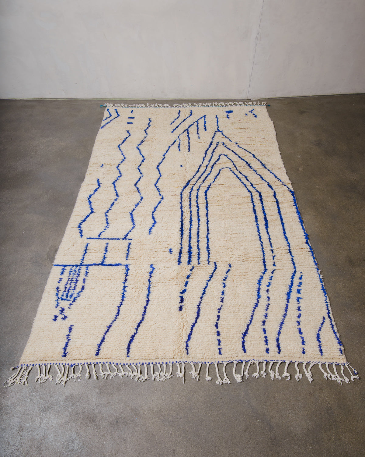 Berberlin Azilal rug made of fluffy wool and cotton, laying flat on a concrete floor.